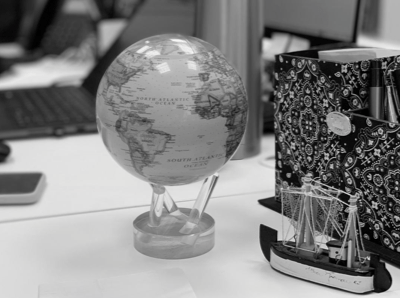 Um globo em cima da mesa, ao lado um barco em miniatura.